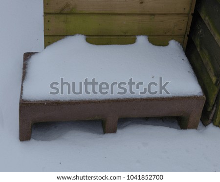 Frozen Stone Water Trough Covered with Snow in a Country Cottage garden in Rural Devon, England, UK
