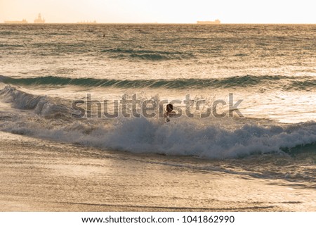 child running on the sea waves at sunset on the Caribbean beach