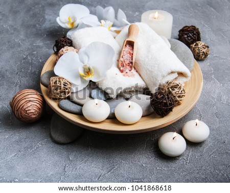 Spa products with white orchids on a gray stone background