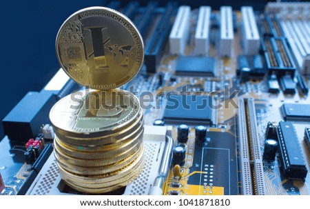 On a motherboard are gold coins of a digital crypto  currency - litecoin. The picture has a blue touch.