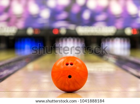 bowling ball ready to roll on a bowling lane with 10 pins in the background