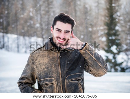 Attractive young man doing call me sign with hand and fingers, cheerful expression looking at camera