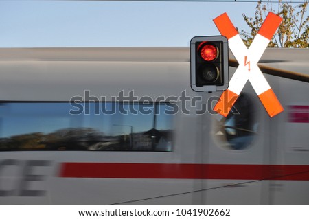 Red traffic light with warning sign at a railroad crossing