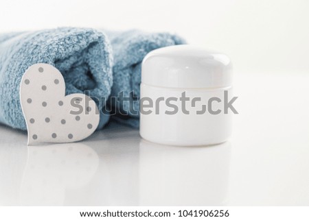 A cream box, next to towels and decration, a close-up