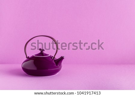 Purple teapot and cups on a lilac background with copy space.