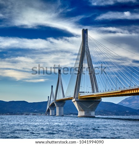 Sunset view on the bridge near Patras. Suspension bridge crossing Corinth Gulf strait, Greece, Europe. Second longest cable-stayed bridge in the world. Dramatic red sky under a Rion-Antirion Bridge.  Royalty-Free Stock Photo #1041994090