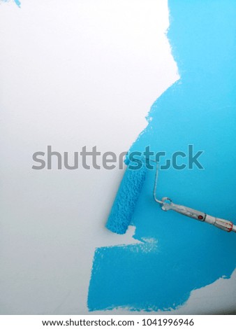 Wall being painted in sky blue paint with paint roller background