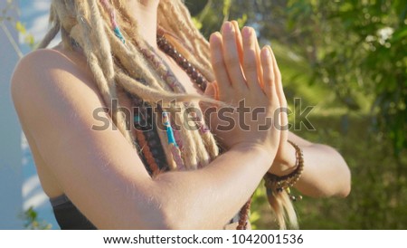 Close-up hands of young woman doing asana yoga with namaskar gesture at backyard of her house.