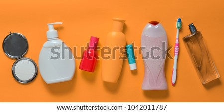 Products for beauty, self-care and hygiene on an orange pastel background. Shampoo, perfume, lipstick, shower gel, toothbrush. Top view. Flat lay.