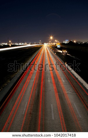 Long exposure of cars traveling through major highway, leaving light trails and conveying motion and progress.  Royalty-Free Stock Photo #1042017418