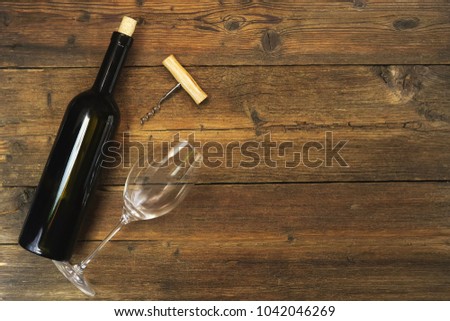 a bottle of wine and a wine glass on a wooden background Royalty-Free Stock Photo #1042046269