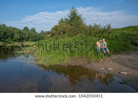 the young couple in the summer in August has come by the motorcycle on a picnic to the river early in the morning. The young man has made the proposal to get married to the girl.