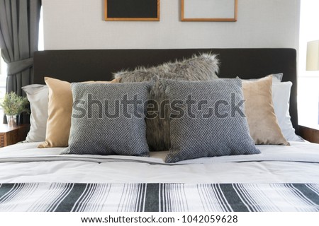 view of a bedroom with picture frame on walls with two grey pillows on bed