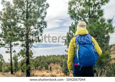 Hiking woman with backpack looking at inspirational mountains landscape and woods. Fitness travel and healthy lifestyle outdoors in fall nature. Female backpacker tourist walking in forest.