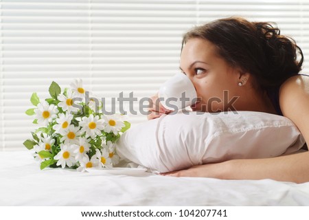 Beautiful Caucasian female lying in a bed of cup on a light background