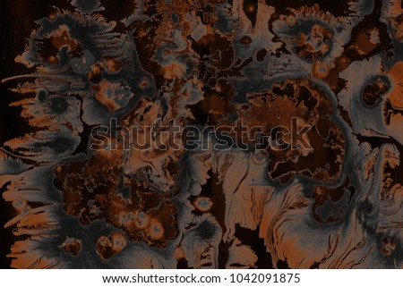 Orange dark wet abstract paint leaks and splashes texture on white watercolor paper background. Natural organic shapes and design.