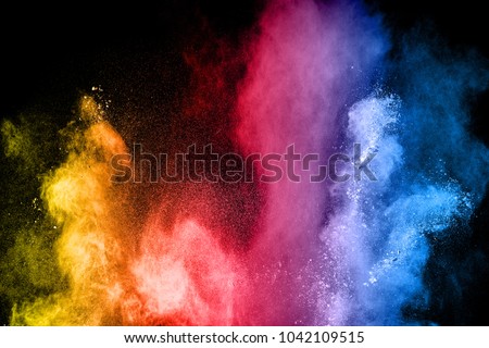 The explosion of multi colored powder. Beautiful rainbow color powder fly away. The cloud of glowing color powder on black background Royalty-Free Stock Photo #1042109515