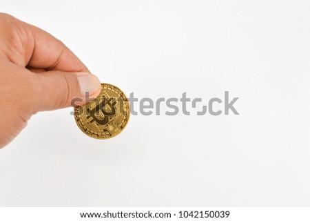 Hand holding golden Bitcoin on white background.