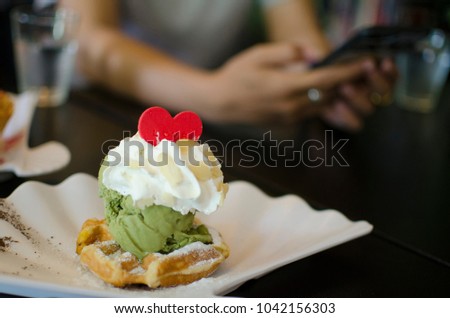 This picture is too soft and burry. Relax in coffee shop and have one Ice cream green tea on waffle topping with whipping cream and red heart cookie. 