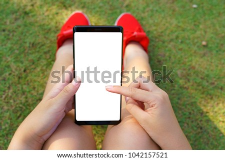 Female red shoe hand holding the smartphone Black and Green nature