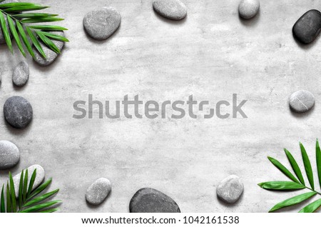 Grey spa background, spa concept, palm leaves and grey stones, top view