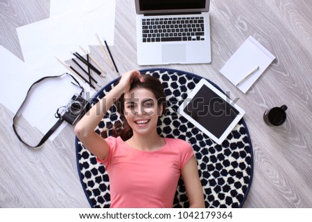 Beautiful young woman with gadgets lying on floor, top view