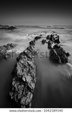 Amazing fine art black & white landscapes photograph of a unique rock formation on the beach at Terengganu. (noise grain soft focus motion blurry due to long exposure) Nature composition