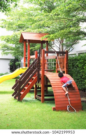 The little boy red shirt uses a rope to climb the slider in the garden.