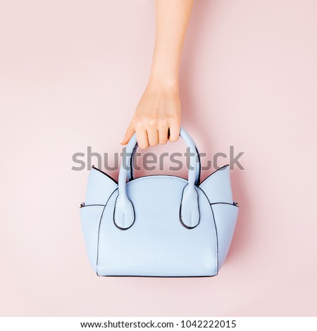 Female hands holds handbag on pink  background . Flat lay, top view. Spring fashion concept in pastel colored Royalty-Free Stock Photo #1042222015