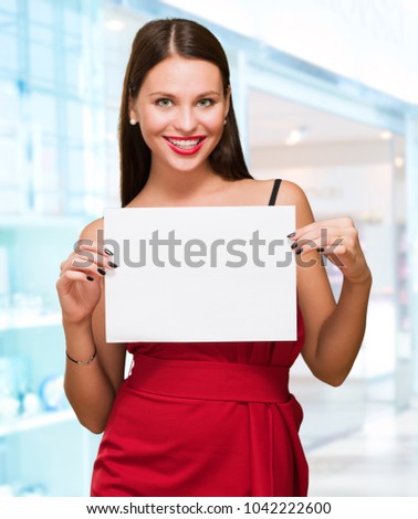 Beautiful woman holding a blank placard at a mall