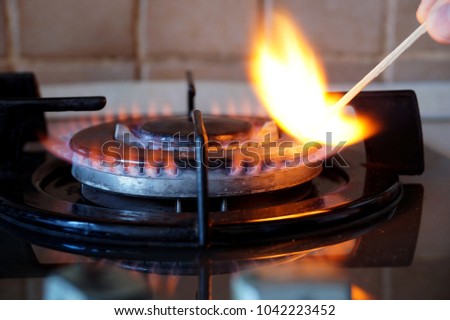 Ignition by a match of a gas ring on the stove Royalty-Free Stock Photo #1042223452