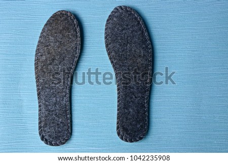 two gray insoles for shoes on a blue background