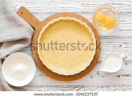 Dough for baking tart (quiche) and baking ingredients above flour, eggs and cream. Top view