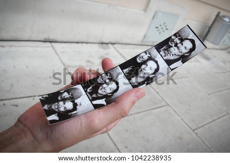 Hand holding a Photo booth strip with the photos of a young couple Royalty-Free Stock Photo #1042238935