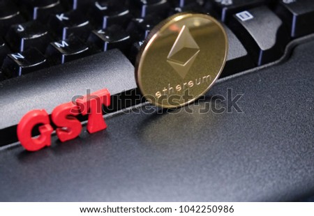 Ethereum cryptocurrency with red 'GST' text against computer keyboard
