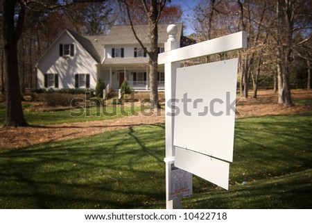 Blank real estate sign in front of a white frame home with a nice yard.