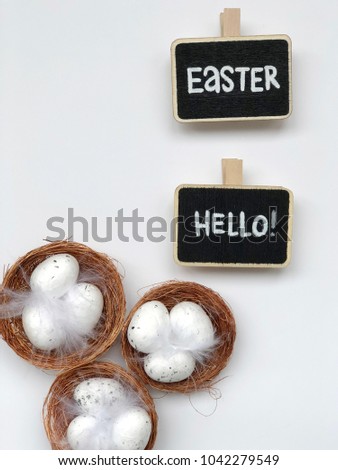 easter eggs in nests on white background with hello easter chalkboards. easter flat lay. 