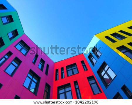 Multi-colored facades of the school with black window frames. Look up from the blue sky Royalty-Free Stock Photo #1042282198