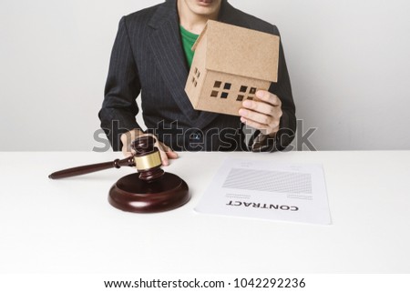 Real estate insurance lawyer working hard job, signing a contract with wooden house model.