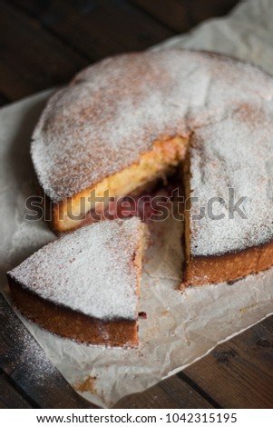 Apple pie with plums with sugar powder on a wooden background