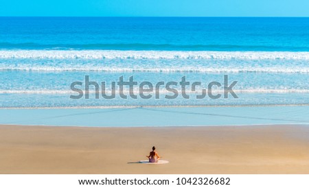 A fit young woman practicing yoga alone on a pristine beach.
