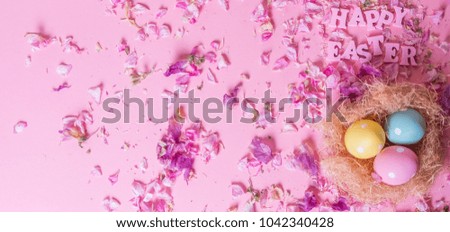 Colorful Easter Eggs in a nest with HAPPY EASTER text against pastel pink background