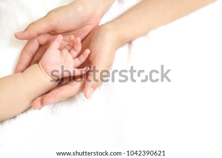 Mother holding the baby's hand.