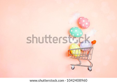 Shopping trolley with Easter eggs and copy space on pink background. Easter shopping and sale.