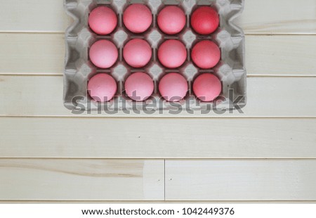 Easter. Pink Easter eggs are in the egg stand. The view from the top. Pastel shades of pink. Wooden background. Kraft cardboard pallet. Spring composition.
