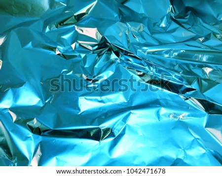 Holographic blue color wrinkled foil. Hologram background of wrinkled abstract foil texture with colors and shiny background