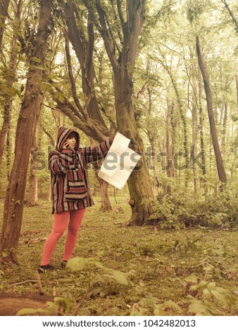 Woman reading map in lush green forest