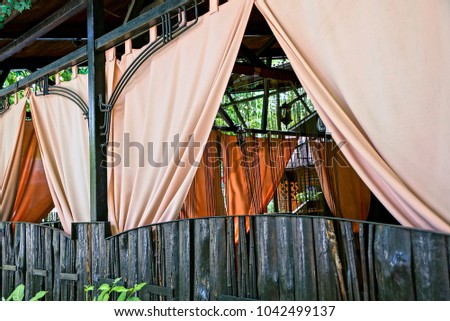 Part of the restaurant with beautiful curtains behind a brown fence