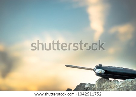 an isolated remote key of a modern vehicle is kept on the rocks and beautiful sunrise in the background 