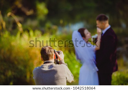 Photographer taking Pictures of the Bride and Groom in the summer park